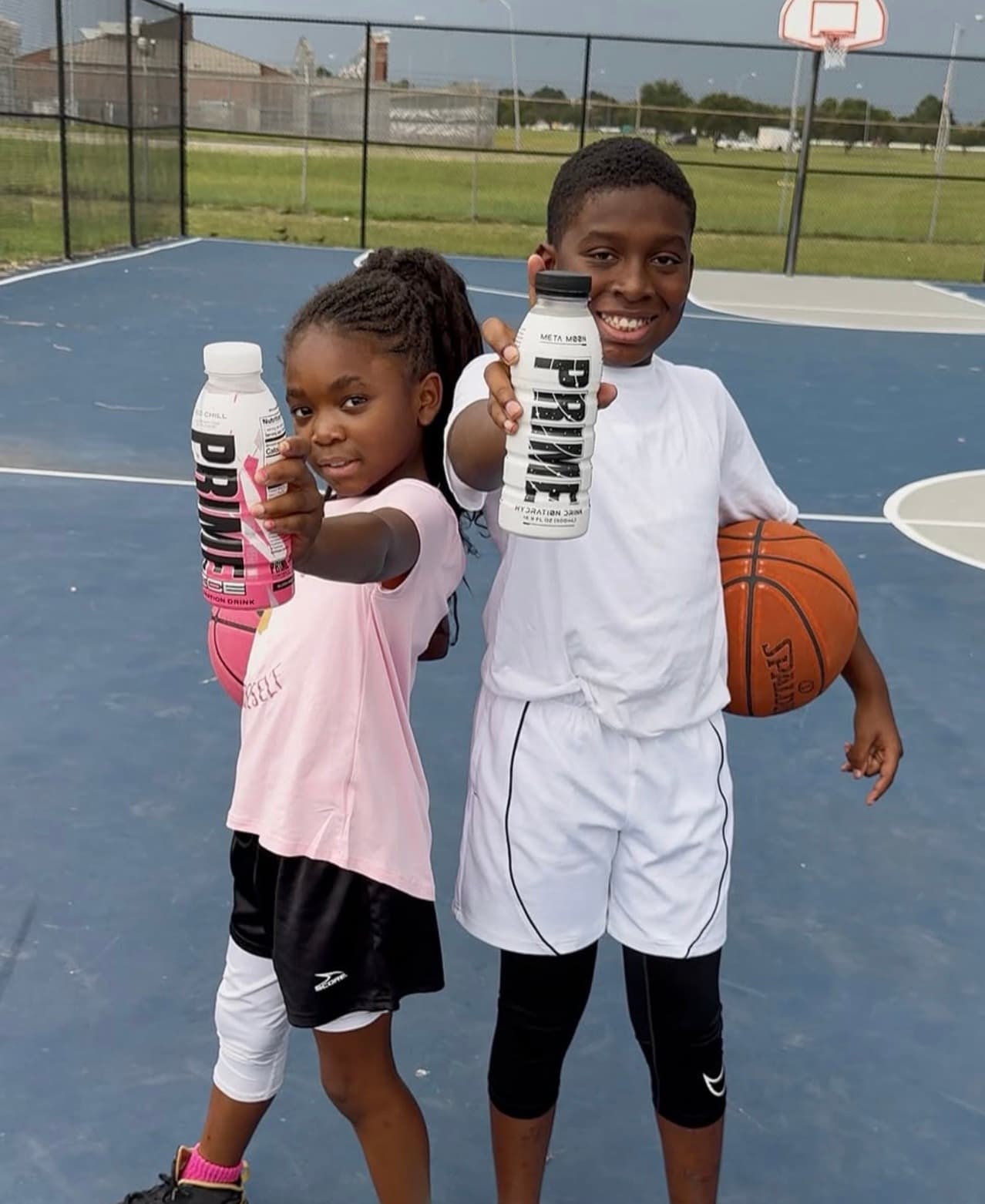 Two young basketball players smiling together on an outdoor court after training